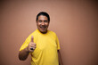 © Odua Images - old asian man wearing yellow tshirt with thumbs up gesture showing agreement of something in plain background isolated