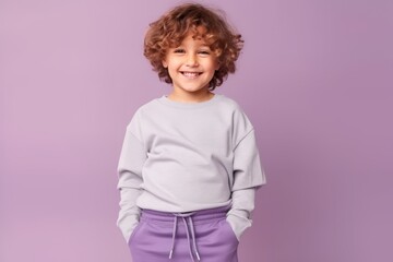 Wall Mural - Cheerful little curly girl smiling and looking at camera isolated over purple background