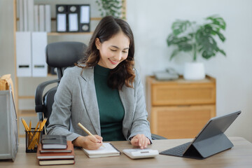 Business woman take notes and use the calculator with calculations about the expenses at the office.