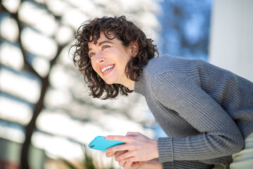 Wall Mural - Attractive young woman with cellphone looking away and smiling