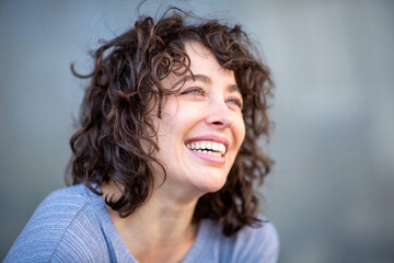 Wall Mural - Cheerful young woman looking away and smiling