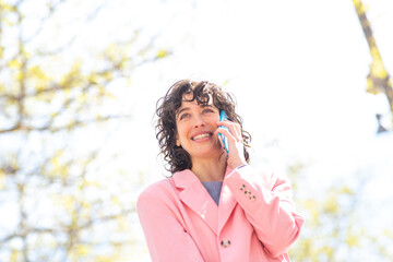 Wall Mural - Beautiful young woman making a phone call walking outside