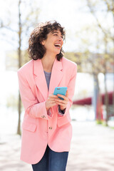 Wall Mural - Attractive woman with cellphone walking outside and smiling