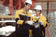 © Nassorn - Latino industrial engineer in white helmet and safety jacket work in heavy metal engineering factory. Technician worker team using tablet computer control metalwork in manufacturing facility, portrait