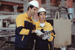 © Nassorn - Latino industrial engineer in white helmet and safety jacket work in heavy metal engineering factory. Technician worker team using tablet computer control metalwork in manufacturing facility, portrait