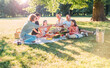 © Soloviova Liudmyla - Big family sitting on the picnic blanket in city park during weekend sunny day. They smiling, laughing and eating watermelon, boiled corn,pie with cold tea. Family values, outdoors activities concept.