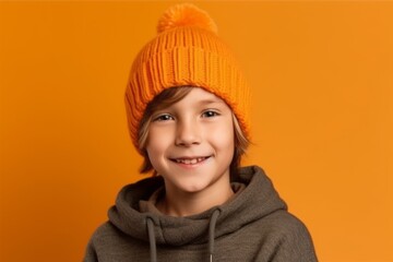 Wall Mural - Portrait of a cute little boy in a knitted hat on a yellow background