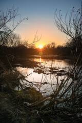 Wall Mural - Autumn sunset over the river. The sun sets below the horizon over the river, which immediately after sunset will be covered with ice. It conveys the atmosphere of autumn melancholy.