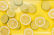 lemon and lime slices in water on yellow background