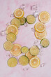 lemon and lime slices and ice in water on pink marble background