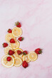 strawberries and lemons on pink marble background