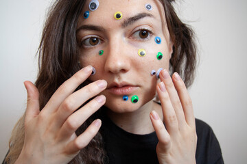 Young Ukrainian girl with white skin and dark hair with big eyes and stickers on her face emotionally depressed mental health issues portrait scared surprised emotions eyesight problems close-up skin 