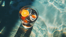Summer Cocktail With Lemon And Ice Next To Swimming Pool And Blue Sky Background.