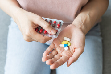 Sick ill asian young woman, girl hand taking tablet pill capsule out from blister pack, painkiller medicine from stomach pain, head ache, pain for treatment, take drug or vitamin at home, health care.