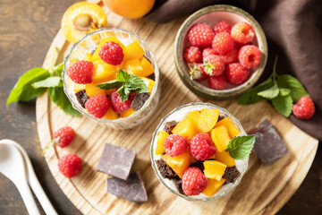 Wall Mural - Summer healthy diet breakfast, snack concept. Triffle of chocolate biscuit with yogurt and fresh berries and fruits. Two portioned glass parfafait dessert. View from above.