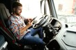 © Serhii - Man truck driver sitting behind wheel of car and holding digital tablet in his hands