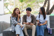 © amnaj - Group Of Young Asian Students Collaborating Outdoors at University. Teamwork and Knowledge Sharing. Asian Students Engaged in Collaborative Learning Outdoors.