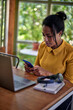 © kerkezz - A young woman sitting in front of a laptop and typing a message on the phone.