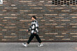 © Evgeny - young man walks down the street in front of a brick wall