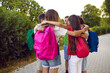 © Studio Romantic - Team of school kids huddling in the park. Group of happy children with backpacks playing games together. Little friends standing on a path and hugging each other. Friendship and teamwork concepts