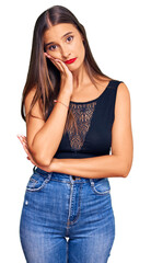 Wall Mural - Young hispanic woman wearing casual clothes thinking looking tired and bored with depression problems with crossed arms.