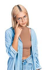 Sticker - Beautiful young blonde woman wearing glasses pointing to the eye watching you gesture, suspicious expression