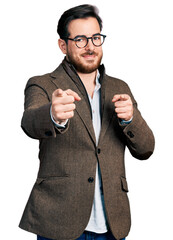 Wall Mural - Young hispanic man wearing business jacket and glasses pointing fingers to camera with happy and funny face. good energy and vibes.