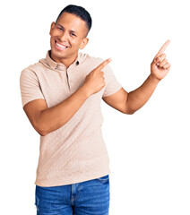 Wall Mural - Young handsome latin man wearing casual clothes smiling and looking at the camera pointing with two hands and fingers to the side.