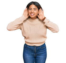 Poster - Young latin girl wearing wool winter sweater trying to hear both hands on ear gesture, curious for gossip. hearing problem, deaf