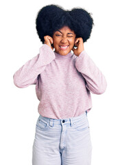 Poster - Young african american girl wearing casual clothes covering ears with fingers with annoyed expression for the noise of loud music. deaf concept.