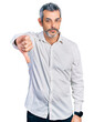 © Krakenimages.com - Middle age hispanic with grey hair wearing casual white shirt looking unhappy and angry showing rejection and negative with thumbs down gesture. bad expression.