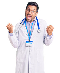 Wall Mural - Young hispanic man wearing doctor uniform and stethoscope very happy and excited doing winner gesture with arms raised, smiling and screaming for success. celebration concept.
