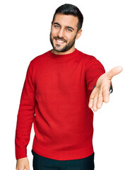 Poster - Young hispanic man wearing casual clothes smiling cheerful offering palm hand giving assistance and acceptance.