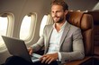 © Adriana - Portrait of handsome businessman working on laptop while flying on airplane
