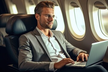 Portrait of handsome businessman working on laptop while flying on airplane