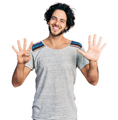 Canvas Print - Young hispanic man wearing casual t shirt showing and pointing up with fingers number nine while smiling confident and happy.