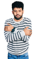 Canvas Print - Young arab man with beard wearing casual striped sweater shaking and freezing for winter cold with sad and shock expression on face