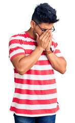 Sticker - Handsome latin american young man wearing casual clothes and glasses with sad expression covering face with hands while crying. depression concept.