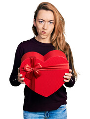 Canvas Print - Young caucasian woman holding valentine gift skeptic and nervous, frowning upset because of problem. negative person.