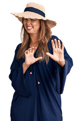 Canvas Print - Middle age hispanic woman wearing summer hat disgusted expression, displeased and fearful doing disgust face because aversion reaction. with hands raised