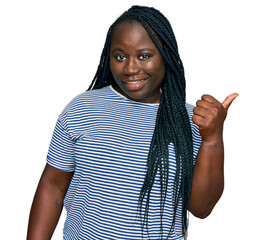 Canvas Print - Young black woman with braids wearing casual clothes smiling with happy face looking and pointing to the side with thumb up.