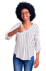 Poster - Young african american woman wearing casual clothes and glasses doing happy thumbs up gesture with hand. approving expression looking at the camera showing success.