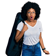 Canvas Print - Young african american woman wearing guitar case scared and amazed with open mouth for surprise, disbelief face