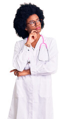 Sticker - Young african american woman wearing doctor coat and stethoscope with hand on chin thinking about question, pensive expression. smiling with thoughtful face. doubt concept.