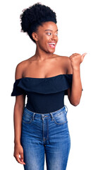 Poster - Young african american woman wearing casual clothes smiling with happy face looking and pointing to the side with thumb up.