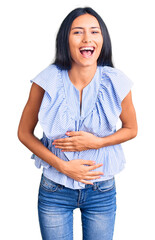 Wall Mural - Young beautiful latin girl wearing casual clothes smiling and laughing hard out loud because funny crazy joke with hands on body.