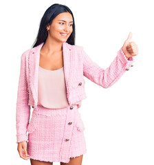 Poster - Young beautiful latin girl wearing business clothes looking proud, smiling doing thumbs up gesture to the side