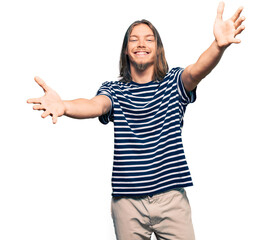 Sticker - Handsome caucasian man with long hair wearing casual striped t-shirt looking at the camera smiling with open arms for hug. cheerful expression embracing happiness.