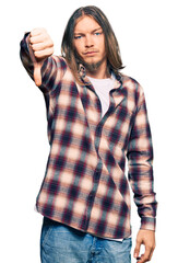 Sticker - Handsome caucasian man with long hair wearing hipster shirt looking unhappy and angry showing rejection and negative with thumbs down gesture. bad expression.