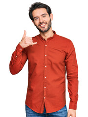 Sticker - Young hispanic man wearing casual clothes smiling doing phone gesture with hand and fingers like talking on the telephone. communicating concepts.